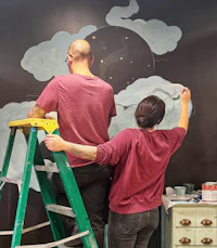 two people painting a mural on a wall